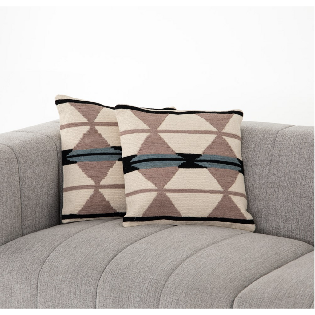 two rust patterned pillows on grey couch